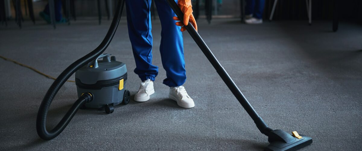 Cleaning lady using a canister vacuum cleaner